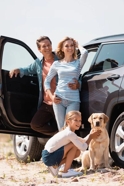 Selective Focus Man Embracing Wife Daughter Golden Retriever Auto Outdoors — Stock Photo, Image