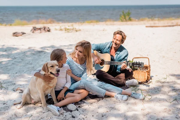 Kocası Sahilde Akustik Gitar Çalarken Bir Kadın Golden Retriever Kızını — Stok fotoğraf