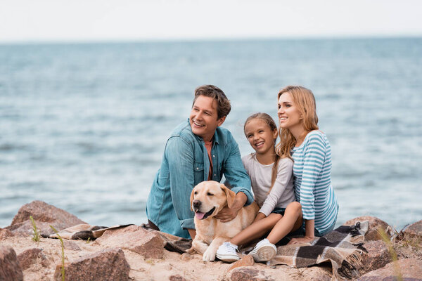 Селективный фокус семьи с золотистым ретривером, сидящим на одеяле на пляже 