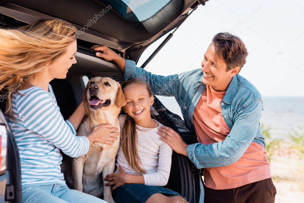 Selective focus of family with golden retriever sitting in truck of auto 