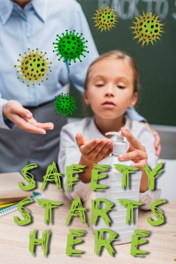 Okullu kızın öğretmeninin yanına el dezenfektanı sürmesinin seçici odağı ve güvenlik burada, sınıfta harflerle başlıyor. 