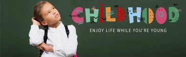 panoramic shot of thoughtful schoolgirl touching head and looking up near chalkboard with childhood, enjoy life while you are young lettering   clipart