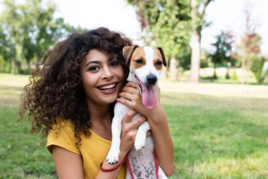 Köpeği tutan ve kameraya bakan genç bir kadının seçici odağı.