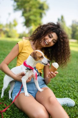 Köpeği tutan ve dondurma veren genç bir kadının seçici odak noktası.