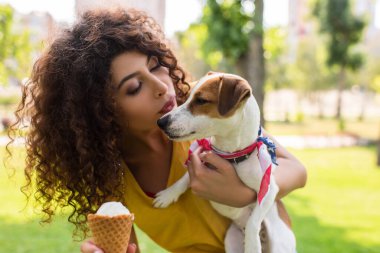 Selective focus of young woman looking at dog and making blowing kiss clipart