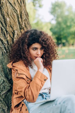 Parkta dizüstü bilgisayara bakan dalgın serbest çalışanın seçici odak noktası 