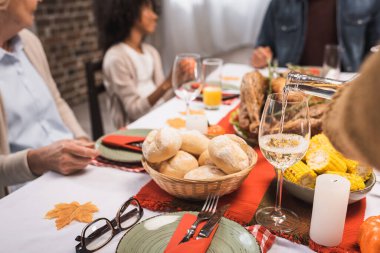 selective focus of multicultural family celebrating thanksgiving at table served with delicious dinner clipart