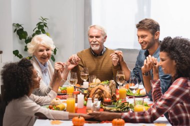Neşeli bir aile el ele tutuşup Afro-Amerikan kızına bakıyor.