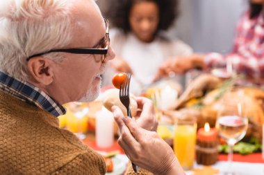 Şükran Günü 'nde ailesiyle birlikte Cherry Domates' le çatal tutan yaşlı kadının seçici odak noktası. 