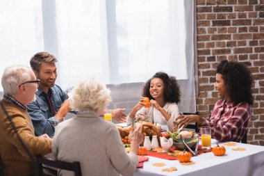 Evde şükran günü yemeğinin yanında oturan çok kültürlü ailenin seçici odağı. 