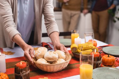 Yaşlı bir kadının Şükran Günü 'nde masaya çöreklerle sepet koyması. 