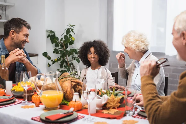 老年妇女在感恩节晚宴上与非洲裔美国孙女交谈的选择性焦点 — 图库照片