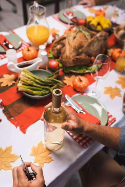 cropped view of man near bottle of white wine at table served with thanksgiving dinner
