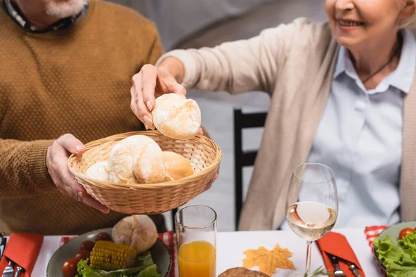 Cropped View Senior Woman Taking Bun Wicker Basket Husband Table — Stock Photo, Image