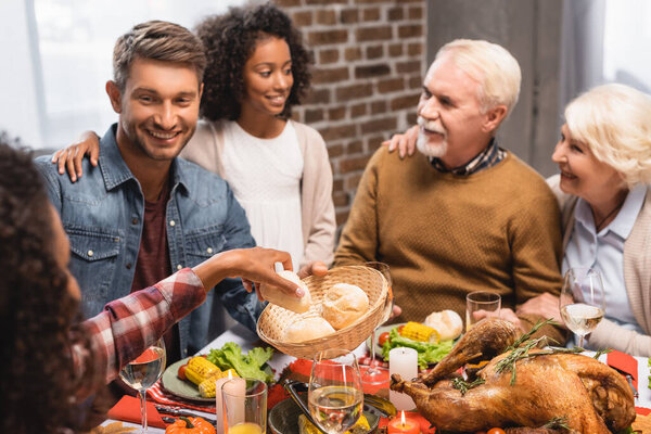 selective focus of african american girl taking bun near family on thanksgiving 