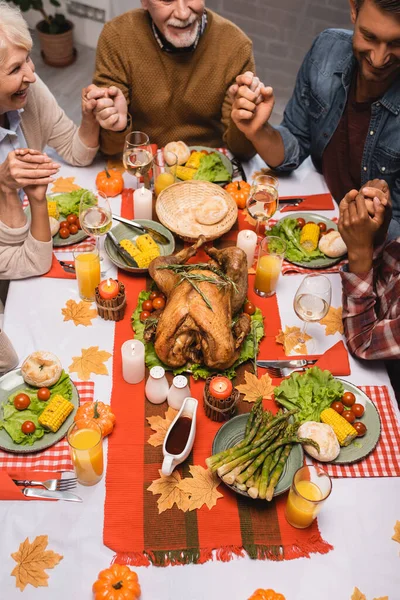 Masada oturup el ele tutuşan neşeli aile manzarası