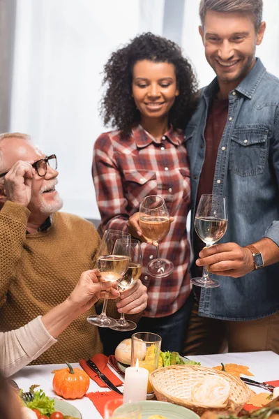 感謝祭の夕食の間に楽しい多文化家族のクリンクワイングラスの選択的な焦点 — ストック写真