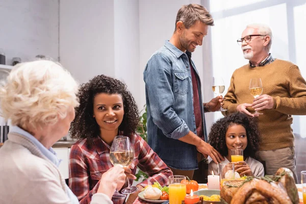 Joyful Multicultural Family Holding Wine Glasses Talking While Celebrating Thanksgiving — Stock Photo, Image