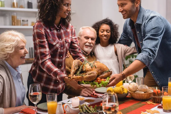 感謝祭の夕食の間に家族の近くの夫に七面鳥を与えるアフリカ系アメリカ人女性の選択的な焦点 — ストック写真