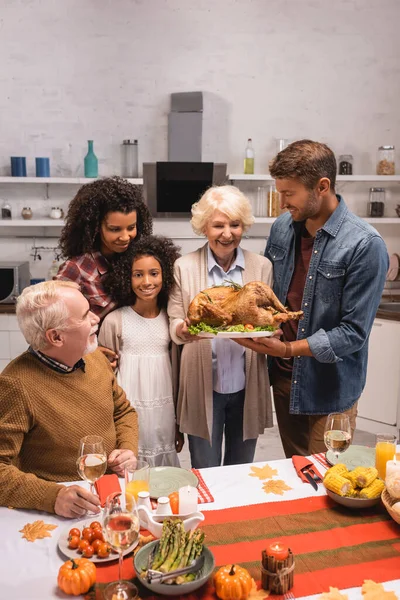 Selective Focus Elderly Woman Holing Turkey Multiethnic Family Thanksgiving Dinner — Stock Photo, Image