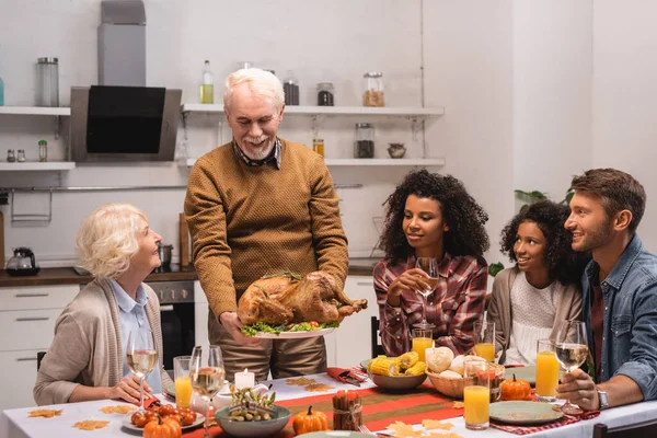 stock image Selective focus of senior man holding delicious turkey near multicultural family  