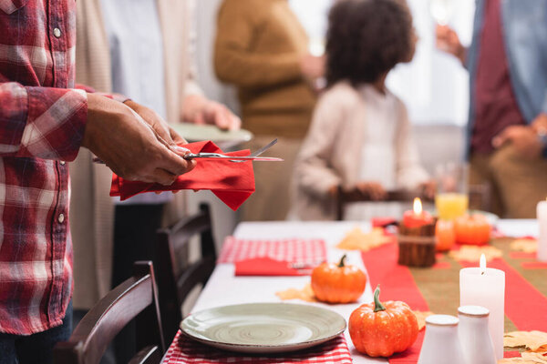 Selective focus of african american woman holding cutlery near decorations on table during thanksgiving celebration 
