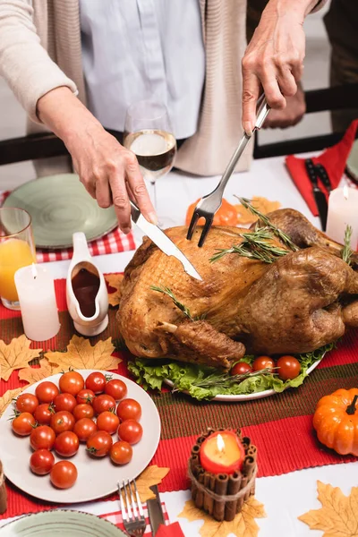 Masadaki süslemelerin yanında hindiyi kesen yaşlı kadın görüntüsü. 
