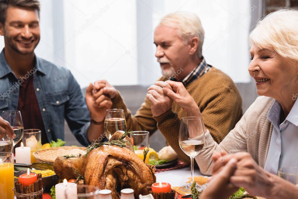 selective focus of family with closed eyes holding hands on thanksgiving 