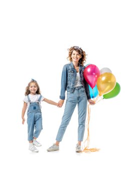 Anne ve kızı renkli balonlarla el ele tutuşup beyazlar üzerinde izole oldular.