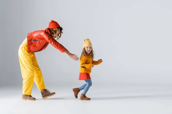 Renkli Kırmızı Sarı Elbiseli Anne Kızın Gri Arka Planda Koşuşan — Stok fotoğraf