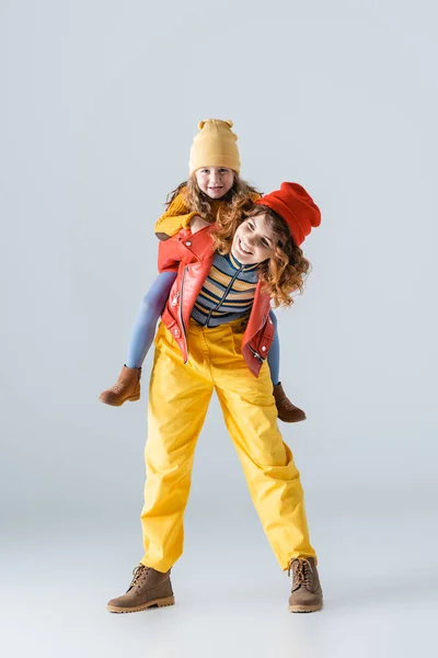 Mãe Filha Roupas Coloridas Vermelhas Amarelas Piggybacking Fundo Cinza — Fotografia de Stock