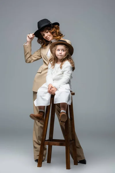 Mãe Elegante Posando Perto Filha Cadeira Cinza — Fotografia de Stock