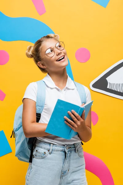 Dreamy Schoolchild Eyeglasses Holding Book Looking Away Yellow Background Abstract — Stock Photo, Image