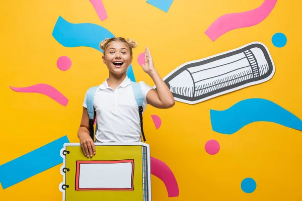 Niño Emocionado Con Maqueta Cuaderno Levantando Mano Sobre Fondo Amarillo —  Fotos de Stock