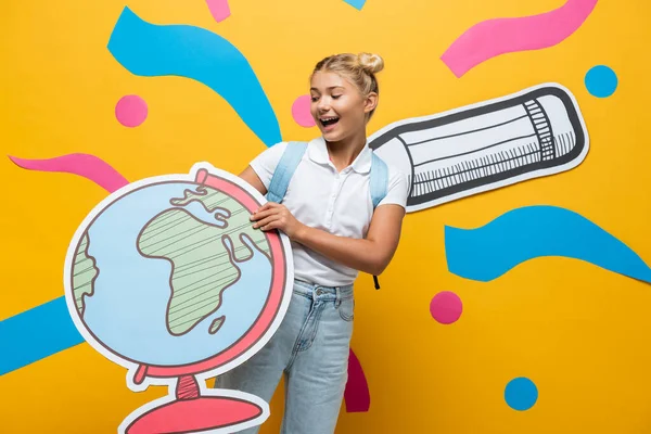 Joyful Schoolgirl Holding Globe Maquette Yellow Background Paper Pencil Abstract — Stock Photo, Image
