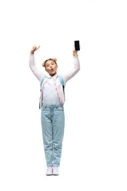 Heyecanlı liseli kız beyaz arka planda boş ekranlı akıllı telefonu işaret ediyor.
