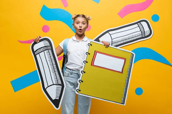 Surprised Schoolgirl Holding Paper Pencil Notebook Yellow Background — Stock Photo, Image