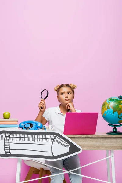 Pensive Child Holding Loupe Telephone Laptop Paper Art Desk Pink — Stock Photo, Image