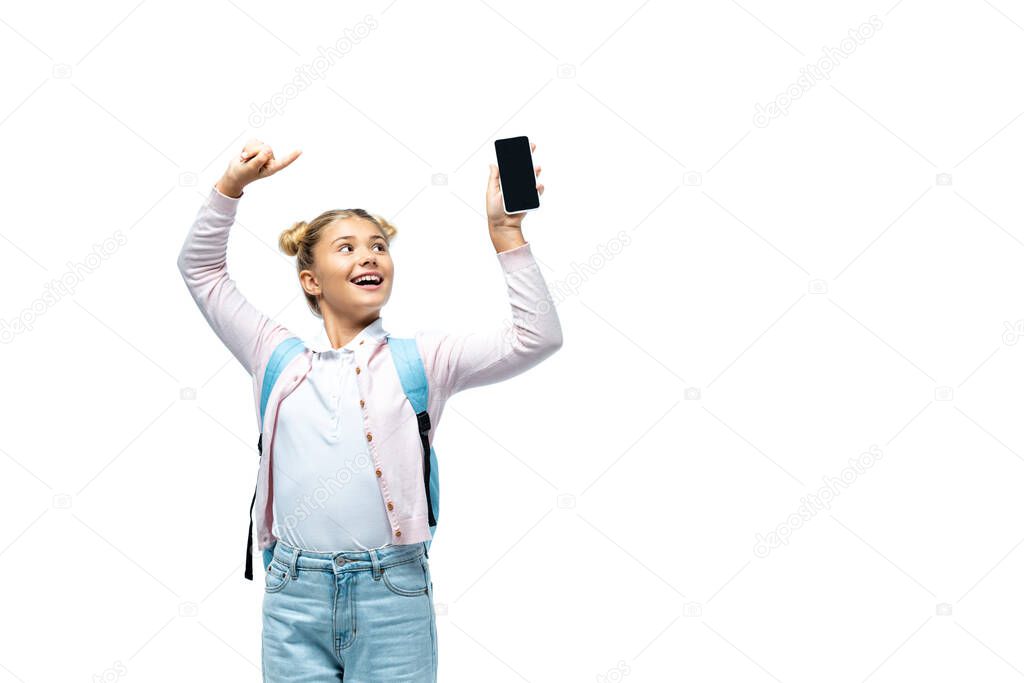 Girl with backpack pointing with finger at smartphone isolated on white 