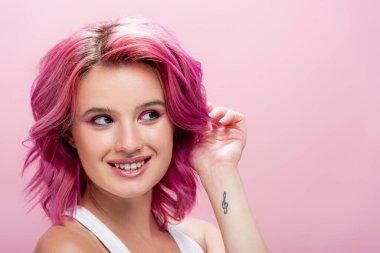 Renkli saçlı ve makyajlı genç bir kadın. Yüzüne yakın poz veriyor. Pembe üzerinde izole edilmiş.