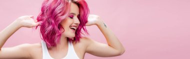 Pembe panoramik çekimde izole edilmiş renkli saçlara dokunan genç bir kadın.
