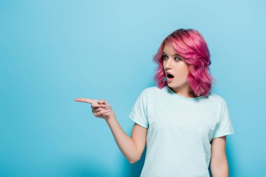 Mavi arka planda pembe saçlı genç kadın şaşırdı.