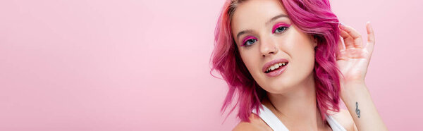 young woman with colorful hair and makeup posing isolated on pink, panoramic shot