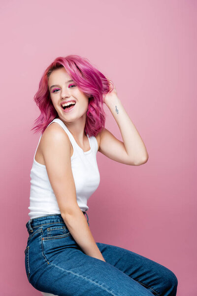 young woman with colorful hair and tattoo smiling isolated on pink