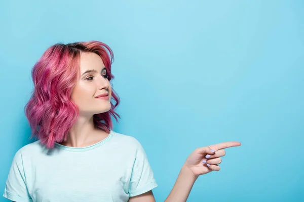 Mujer Joven Con Pelo Rosa Señalando Lado Sobre Fondo Azul — Foto de Stock