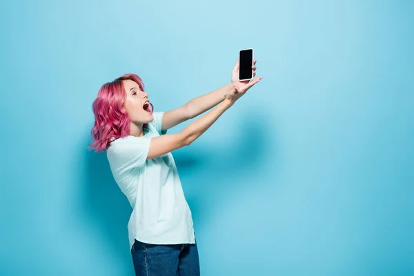 Έκπληκτη Νεαρή Γυναίκα Ροζ Μαλλιά Κρατώντας Smartphone Λευκή Οθόνη Μπλε — Φωτογραφία Αρχείου