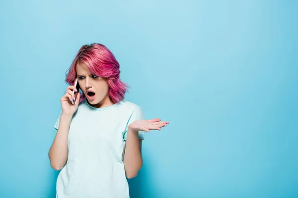 Шокированная Молодая Женщина Розовыми Волосами Разговаривает Смартфоне Синем Фоне — стоковое фото