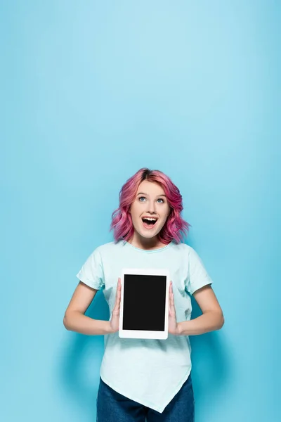 兴奋的年轻女子 一头粉色的头发 带着蓝色背景的空白屏幕 展示数码平板电脑 — 图库照片