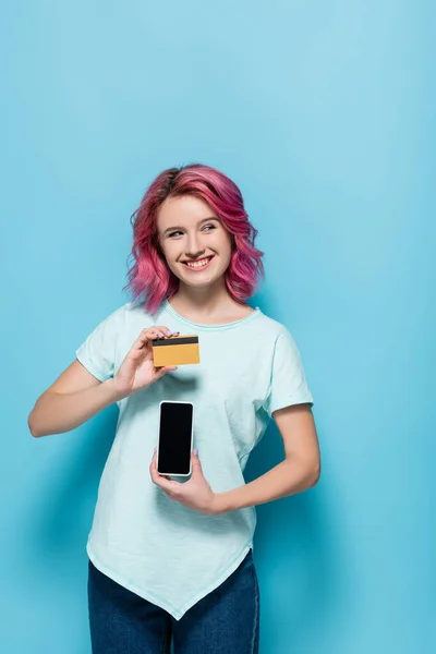 Молодая Женщина Розовыми Волосами Держит Кредитную Карту Смартфон Синем Фоне — стоковое фото