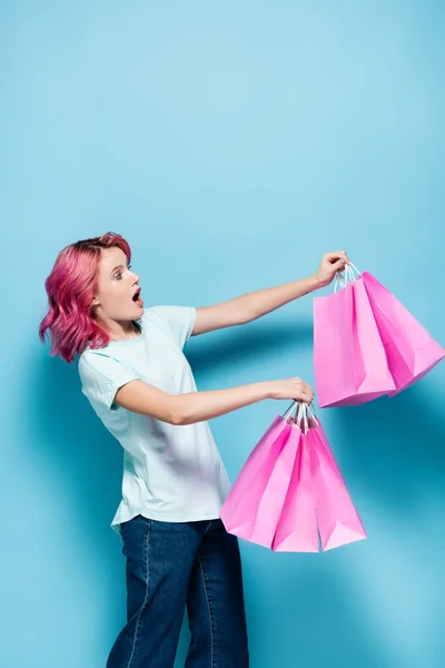 Shocked Young Woman Pink Hair Holding Shopping Bags Blue Background — Stock Photo, Image